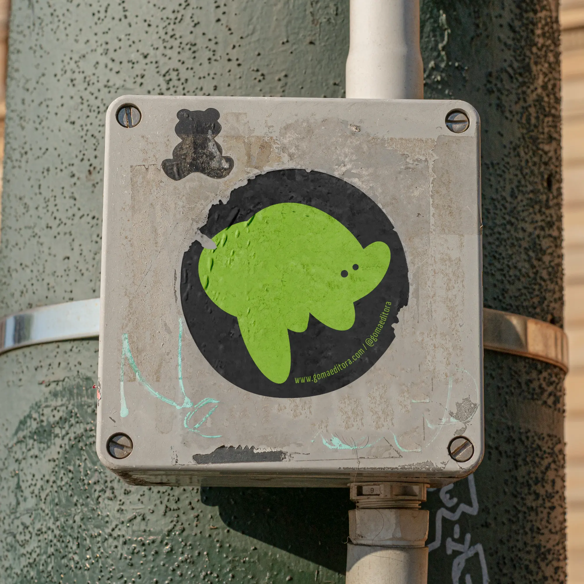 Green Goma character sticker on a utility box.