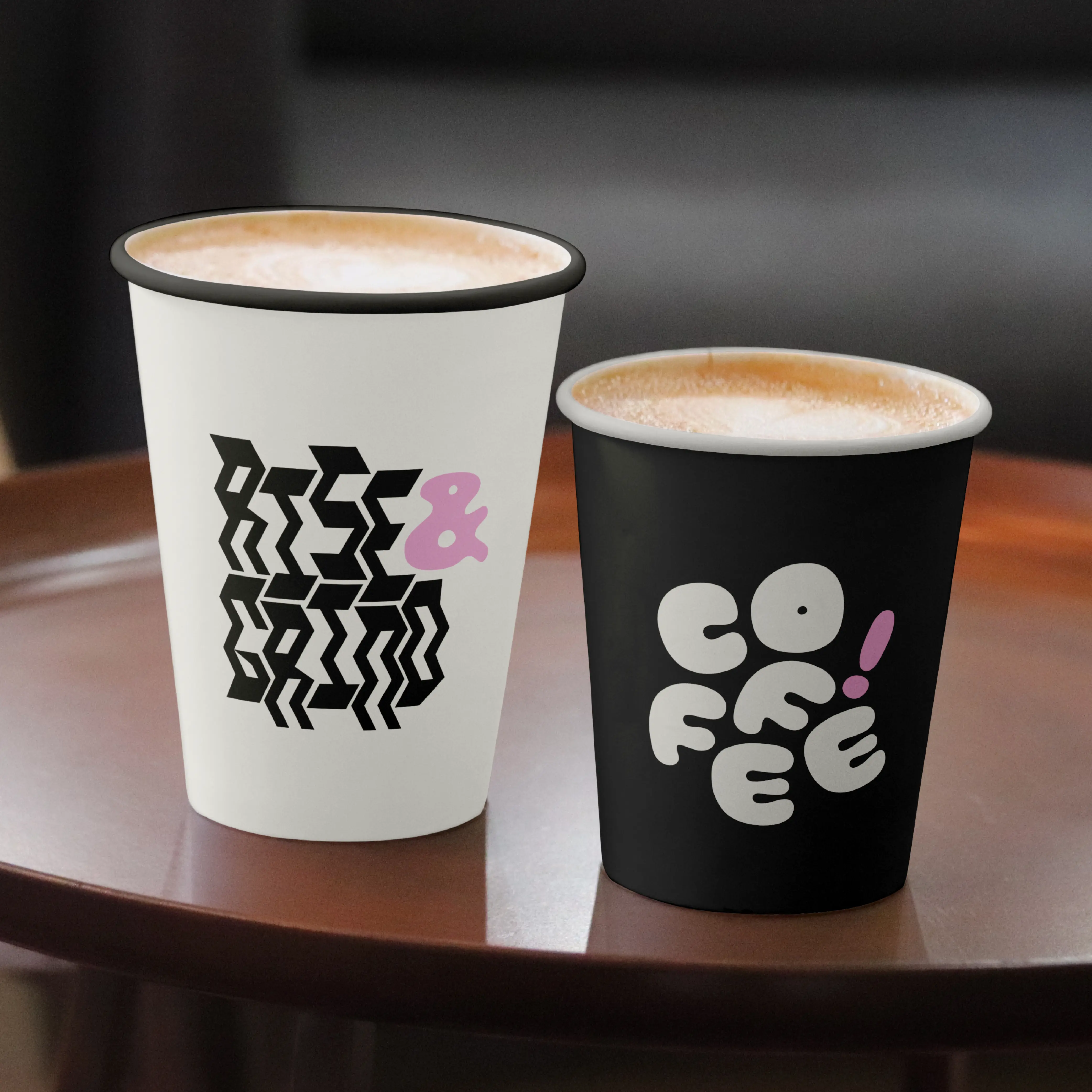 Two takeaway cups printed with Brinca zigzag and rounded lettering.